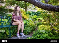 triste-joven-mujer-sentada-en-un-banco-en-el-jardin-mirando-hacia-arriba-orando-hn6nna.jpg